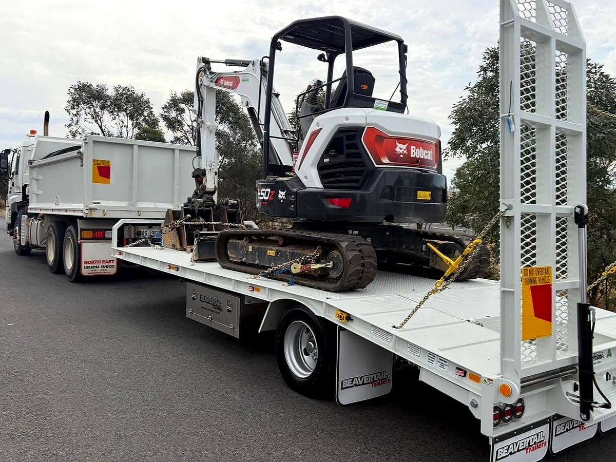 Excavator loaded on a tilt-tray for transport